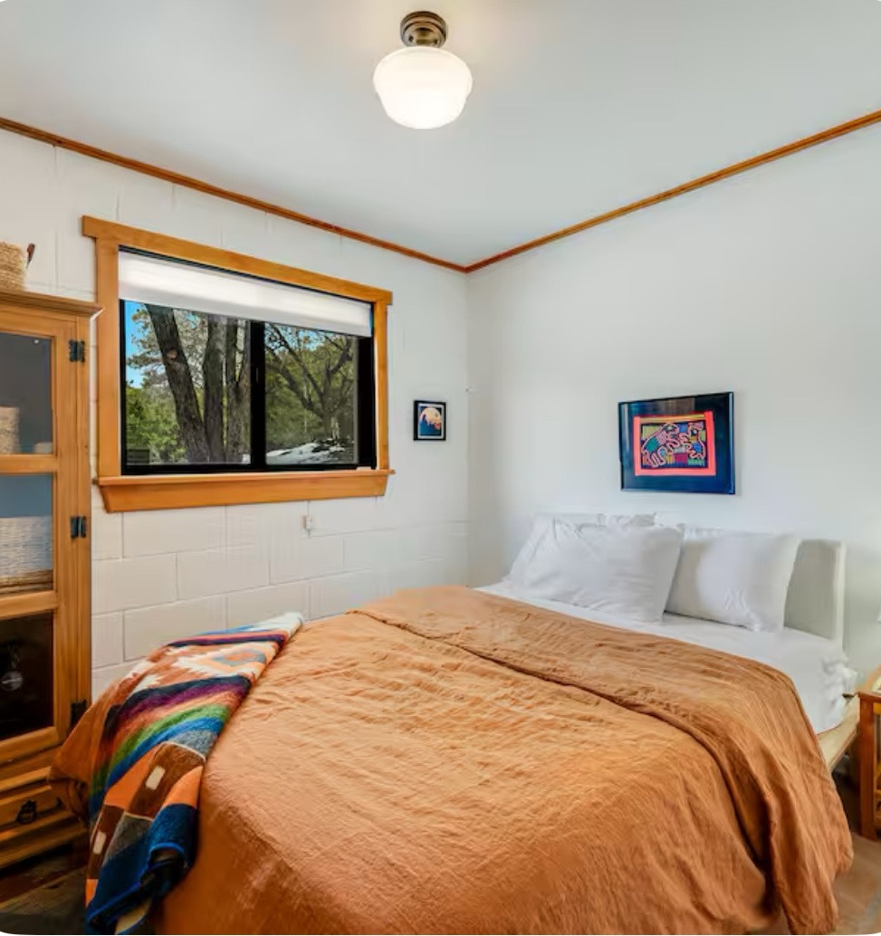 bedroom showcasing a bed, a dresser, and a window that offers a view outside